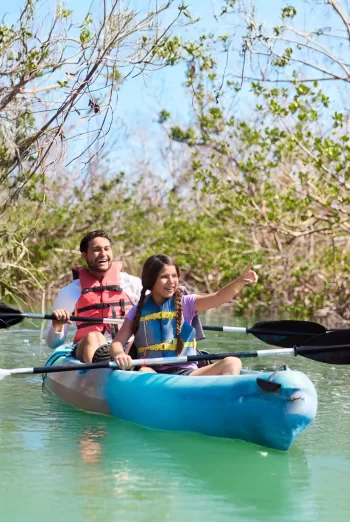 A child and father kayaking in a paddle boat