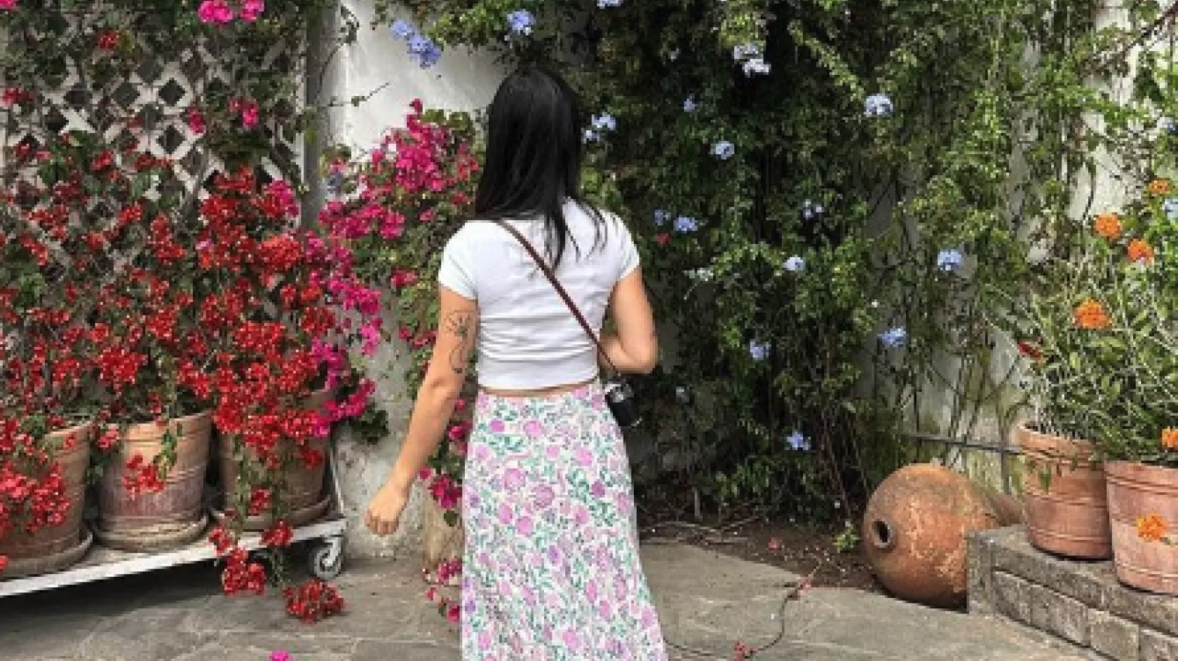 A woman stands in front of a colorful flower wall