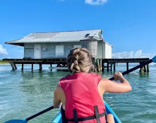 A woman in a pink shirt paddling a blue kayak