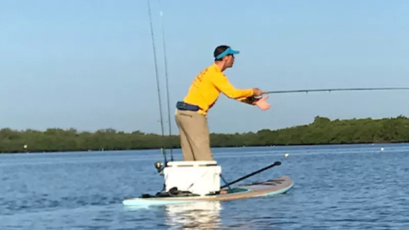 A person fly-fishes on a paddle board in Matlacha